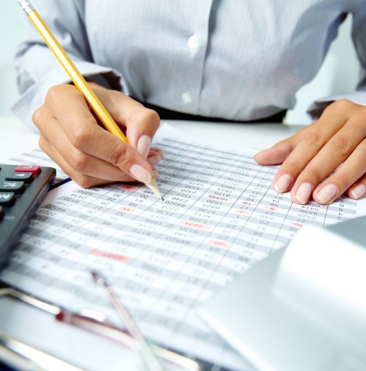 Photo of human hands holding pencil and ticking data in documents